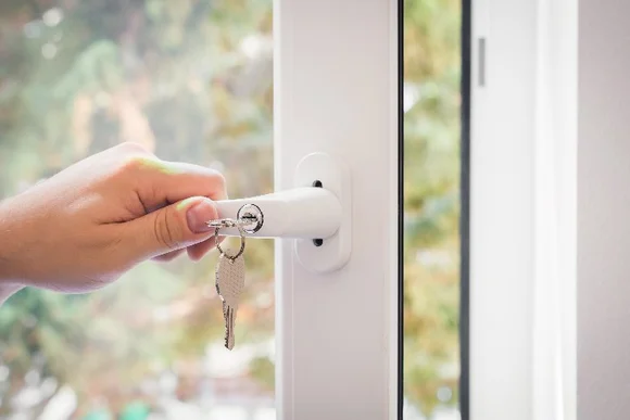 Hand öffnet ein Fenster mit einem Schlüssel.